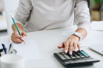 Praca biurowa - pracownik przy biurku, z ołówkiem i kalkulatorem